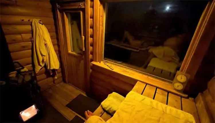 Log sauna Sauna innen mit Saunaofen, Handtüchern und Fenster hinter denm der Nachthimmel zu sehen ist