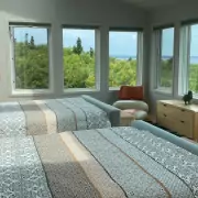 Helles Schlafzimmer mit zwei Doppelbetten und Meerblick Helles Schlafzimmer mit zwei Doppelbetten, moderner Kunst an der Wand und Meerblick durch die Fenster.