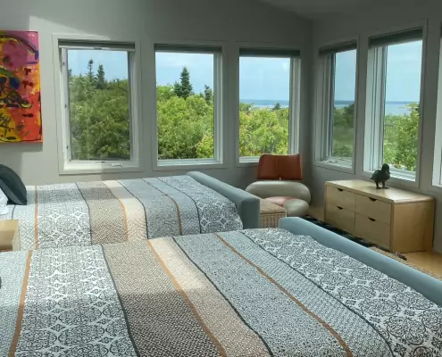 Helles Schlafzimmer mit zwei Doppelbetten und Meerblick Helles Schlafzimmer mit zwei Doppelbetten, moderner Kunst an der Wand und Meerblick durch die Fenster.