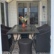 Screenroom Screen room with glass roof and sea view, table set with rattan furniture and fresh bouquet of flowers.