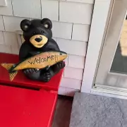 Herzlich Willkommen Deko-Bär mit Fisch in den Pfoten und dem Schriftzug „Welcome“ – herzlicher Willkommensgruß vor dem Eingang.